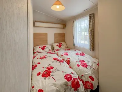 a bedroom with a bed with red flowers on it at Peppy in Newton Stewart