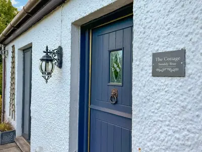 a blue door on a house with a sign on it at The Cottage in Whiting Bay