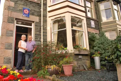 a man and woman standing outside of a house at Laurel Bank Guest House in Keswick