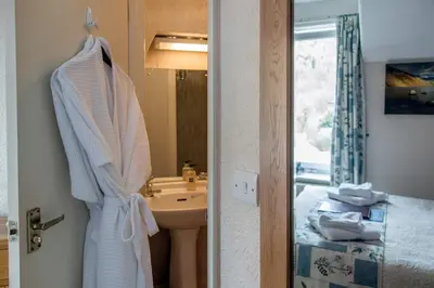 a bathroom with a sink and a robe hanging on a door at Laurel Bank Guest House in Keswick