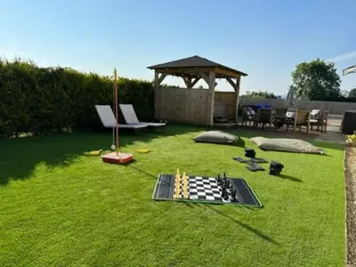 a lawn with a chess board and a gazebo at Bungalow with Hot Tub, BBQ Hut, Golf Net , Large Garden & Play Area in Maybole
