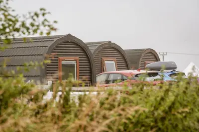 a row of wooden homes with a car parked in front at Unit 2 - Carrock View Camping Pod in Carlisle