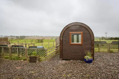 a small wooden shed with a window in a field at Unit 2 - Carrock View Camping Pod in Carlisle