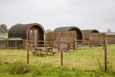 a group of huts in a field behind a fence at Unit 4 - Skiddaw View Camping Pod in Carlisle