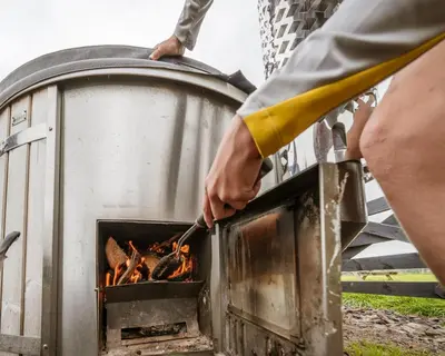 a person cooking food over a fire in an oven at Unit 1 - Dolly Daydream Bell Tent in Carlisle