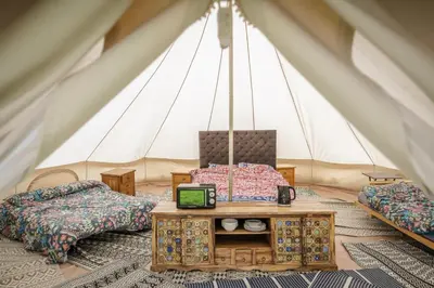 a room with two beds and a table in a tent at Unit 1 - Dolly Daydream Bell Tent in Carlisle