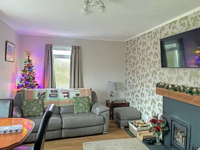 a living room with a couch and a christmas tree at Lilybank Cottage in Doularg