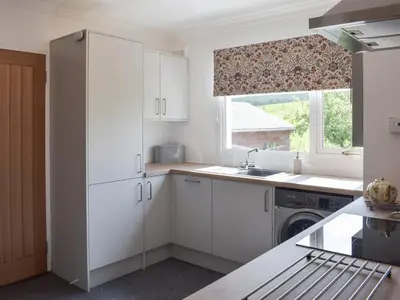 a kitchen with white cabinets and a window at Lilybank Cottage in Doularg