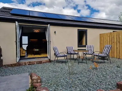 a patio with chairs and a table in front of a house at The Den by Blake View Holidays a peaceful boutique retreat 3 miles from Ennerdale- standard twin or super-king bed available in Rowrah