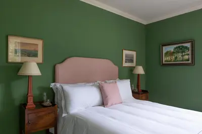 a bedroom with a white bed with green walls at Dabton House in Carronbridge