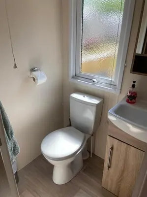 a bathroom with a toilet and a sink and a window at Rhodes Retreat, Lake District in Brigham