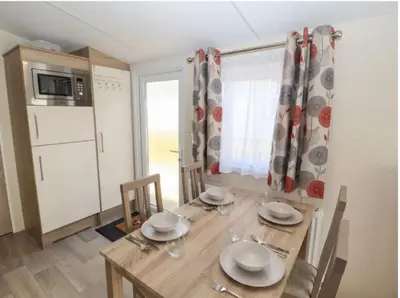 a dining room with a wooden table and a kitchen at Rhodes Retreat, Lake District in Brigham