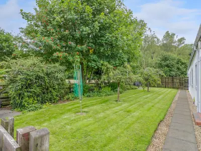 a garden with apple trees and a fence at The Barn at Daldorch in Mauchline