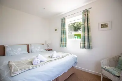 a bedroom with a large white bed with a window at SHELTER STONE - Cottage in the heart of the Lakes in Keswick