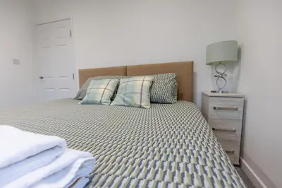 a bedroom with a bed and a night stand with a lamp at SHELTER STONE - Cottage in the heart of the Lakes in Keswick