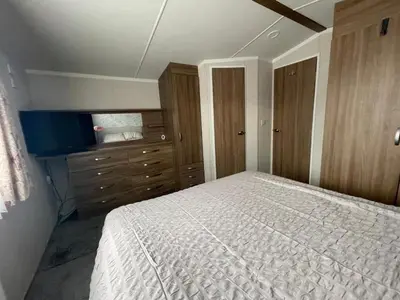 a bedroom with a bed and a dresser at Lake District Stunning Lodge in Plumbland