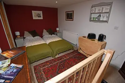 a bedroom with a bed and a wooden table at Helvellyn Room With View - Double or twin in Penrith