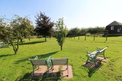 two park benches sitting in a field of grass at Puddleduck Hut Armathwaite with hot tub and dog agility course, perfect for a romantic break in Armathwaite