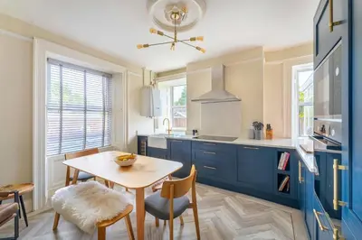 a kitchen with blue cabinets and a table and chairs at Mansefield, Keswick - Sleeps 6 in Keswick