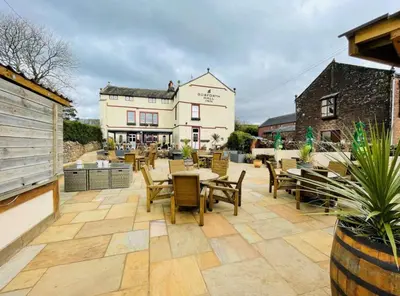 a patio with tables and chairs in front of a building at Gosforth Hall Inn in Gosforth