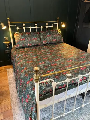 a bedroom with a bed with a floral bedspread at Dinmont Cottage in Dalston