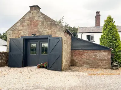 a garage with black doors and a brick building at Dinmont Cottage in Dalston