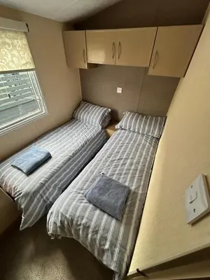 two beds sitting in a small room with a window at The Lake District Caravan in Lamplugh