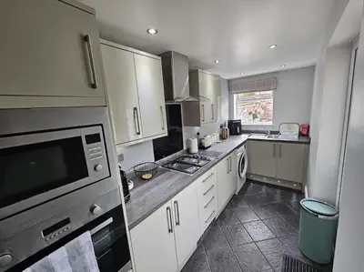 a large kitchen with white cabinets and a microwave at Ashley House, Carlisle in Carlisle