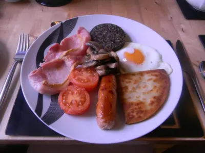 a plate of breakfast food with eggs bacon tomatoes and toast at Harbour Lights Guesthouse in Stranraer
