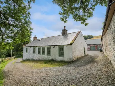 an old white building with green windows on a gravel road at Kilnmark Farmhouse in Thornhill