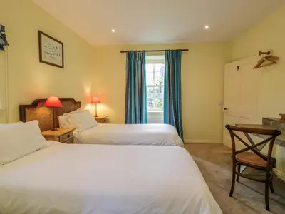 a bedroom with two beds and a desk and a window at Kilnmark Farmhouse in Thornhill