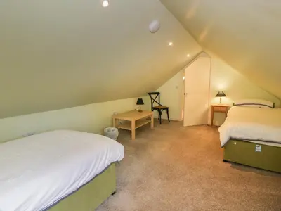 a attic bedroom with two beds and a table at Kilnmark Farmhouse in Thornhill