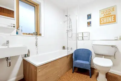 a bathroom with a tub and a toilet and a blue chair at Stylish retreat in Langdale in Chapel Stile