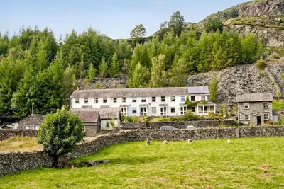 a building in a field next to a stone wall at Stylish retreat in Langdale in Chapel Stile