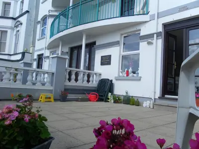 a white building with flowers in front of it at isleofmanholidayapartment in Douglas
