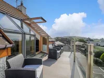 a balcony with couches and chairs on a house at Seascape in Dalbeattie