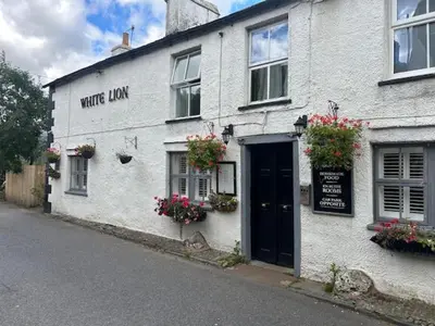 a white building with a black door on a street at The White Lion Inn in Penrith