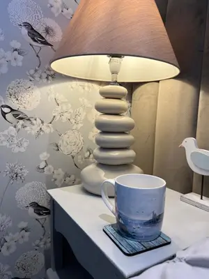 a table with a lamp and a cup on it at Beach room in Ayr