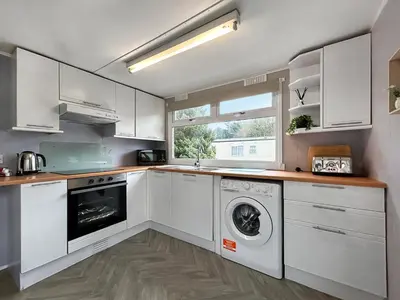 a kitchen with white cabinets and a washer and dryer at Lisset in Newton Stewart