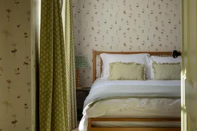 a bedroom with a bed and a wall with flowers at Queensberry Cottage in Thornhill