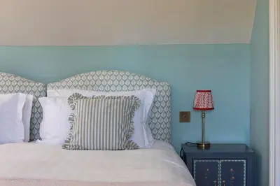 a bed with white pillows and a lamp on a table at Queensberry Cottage in Thornhill