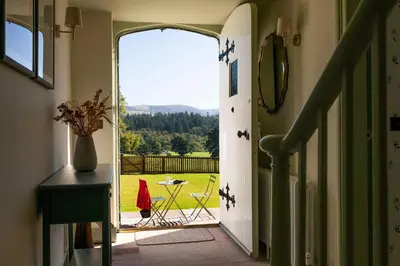 a hallway with an open door to a yard at Queensberry Cottage in Thornhill
