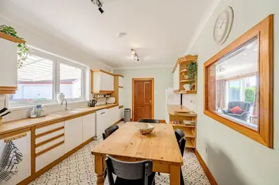 a kitchen with a wooden table and a dining room at Anthony House in Kippford
