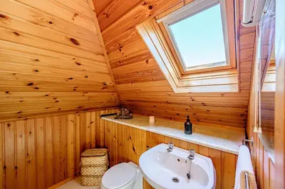 a bathroom with a toilet and a sink and a window at Anthony House in Kippford
