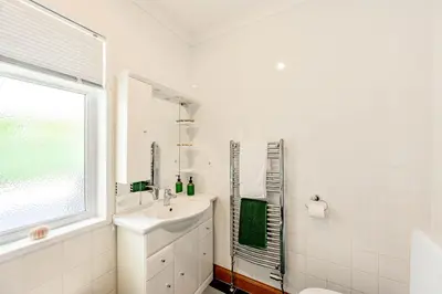 a white bathroom with a sink and a window at Anthony House in Kippford