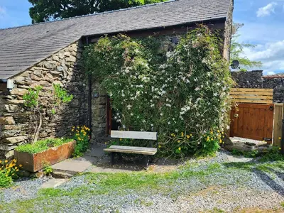 a wooden bench sitting in front of a stone building at 1 Bed in Eskdale 95105 in Eskdale