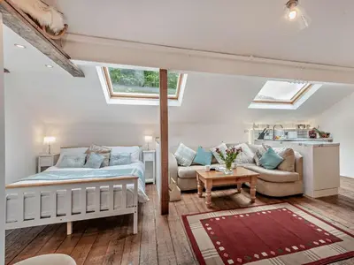 a bedroom with a bed and a couch and windows at 1 Bed in Eskdale 95105 in Eskdale