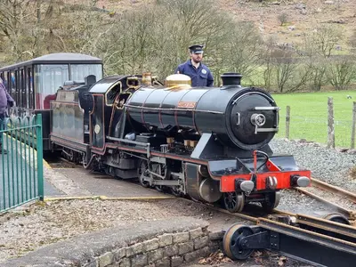a man is driving a small train on the tracks at 1 Bed in Eskdale 95105 in Eskdale