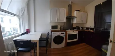 a kitchen with a table and a stove top oven at Flat 2 Douglas Head Road in Douglas