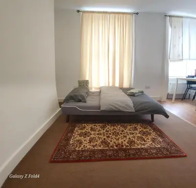 a bed in a bedroom with a rug and a window at Flat 2 Douglas Head Road in Douglas